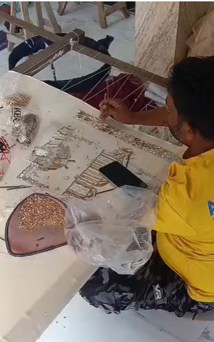 Artisan hand embroidery with beads and sequins on a wooden frame